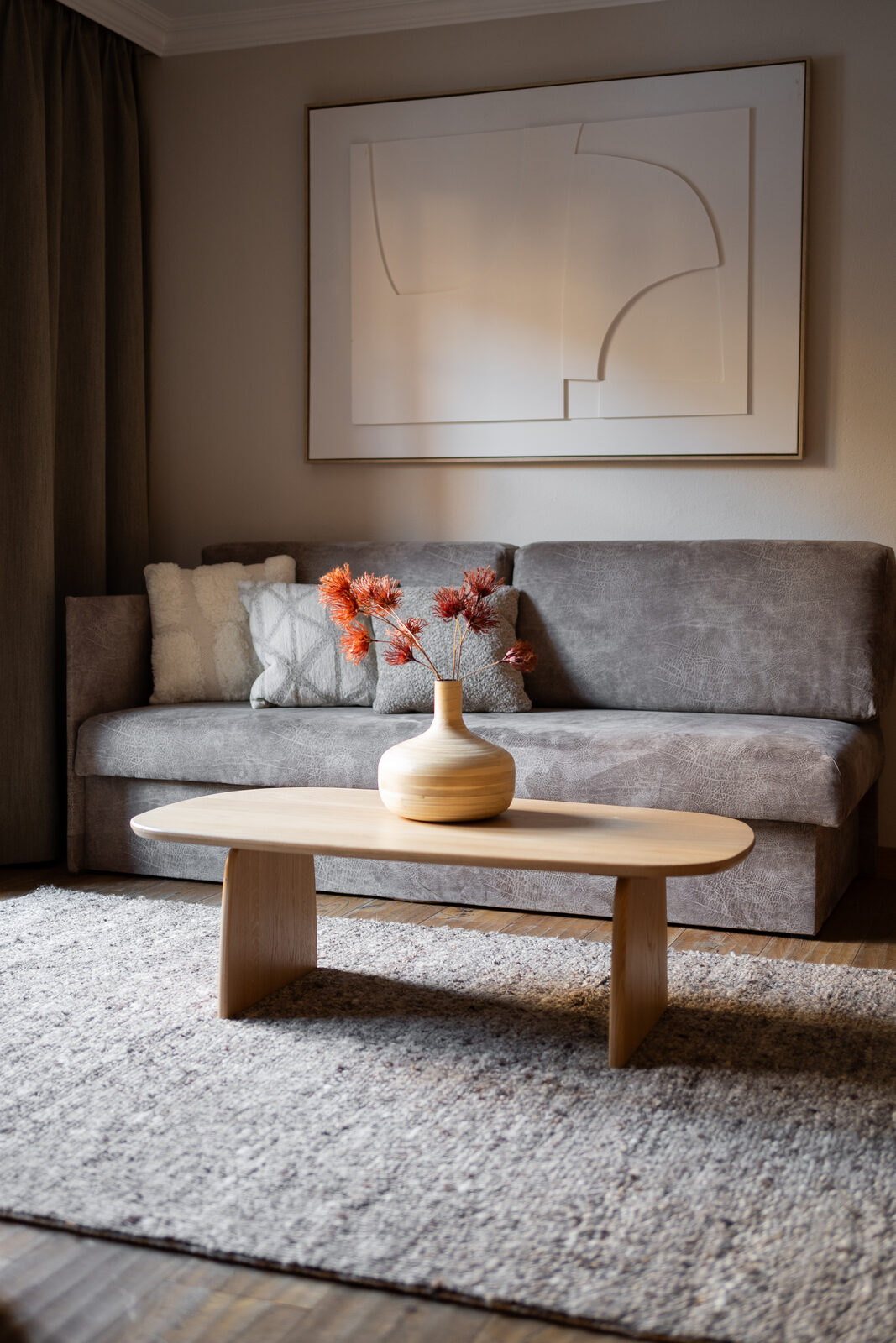 Living area in a 3-room suite, grey sofa under a contemporary line drawing.